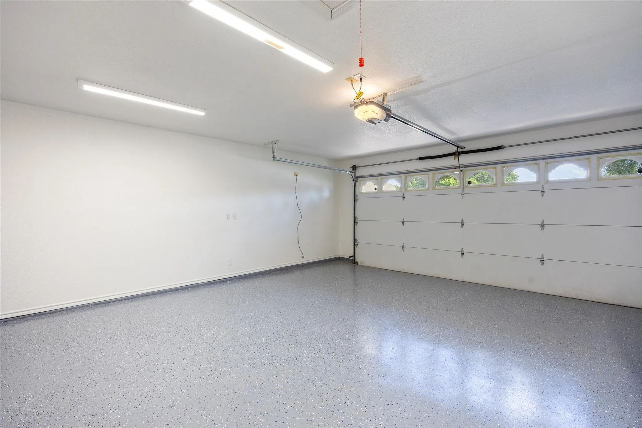 Garage featuring epoxy-coated flooring, overhead fluorescent lighting, and an overhead door opener