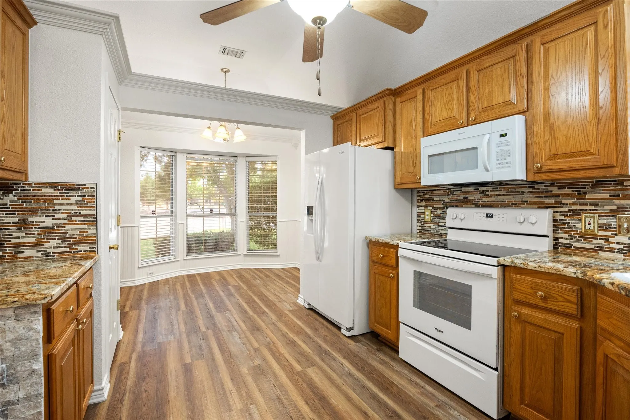 Wood-finish flooring throughout, bay windows with blinds, recessed lighting, and a ceiling fan