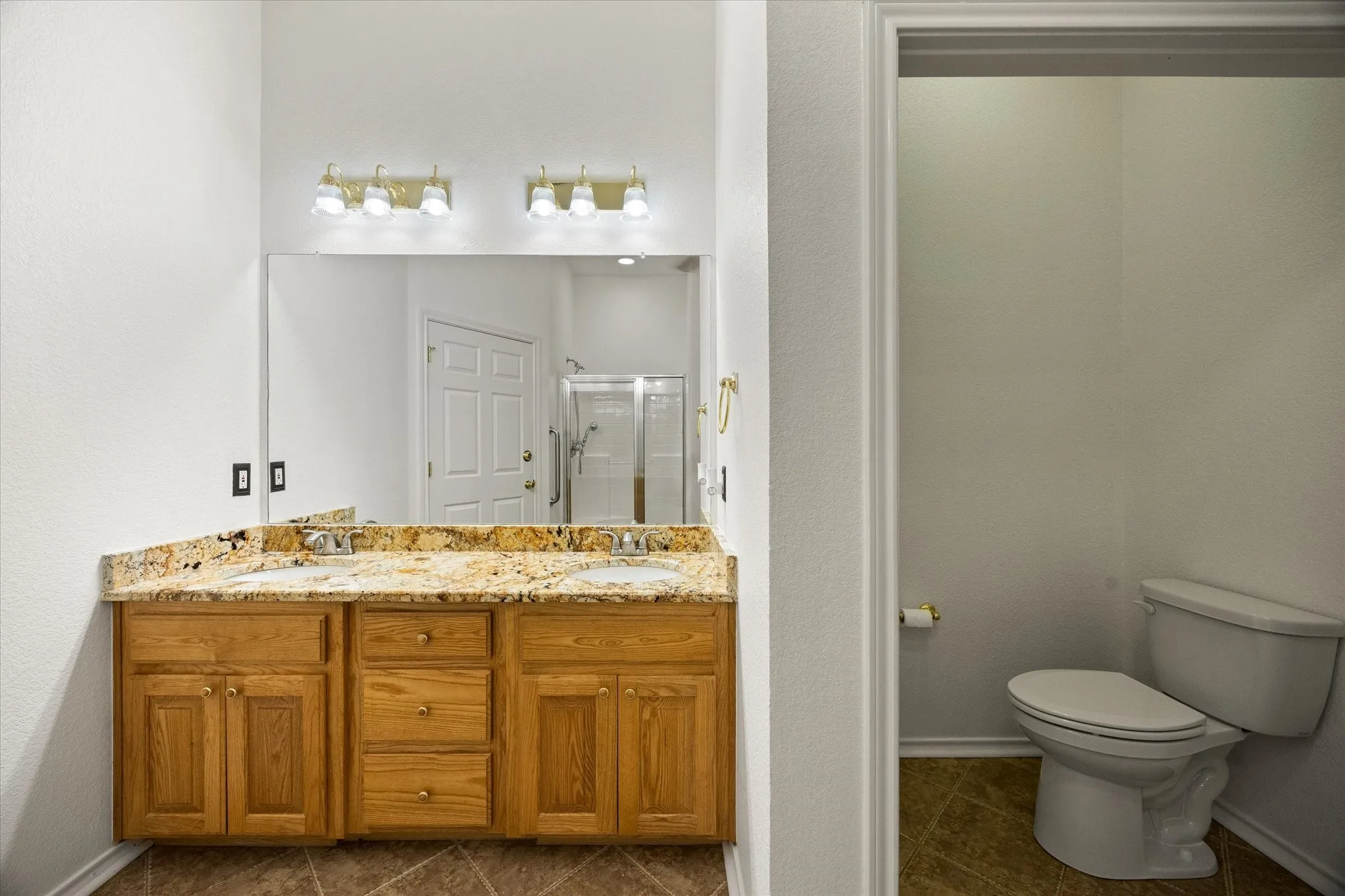 Double vanity with granite countertop and dual undermount sinks, tile flooring