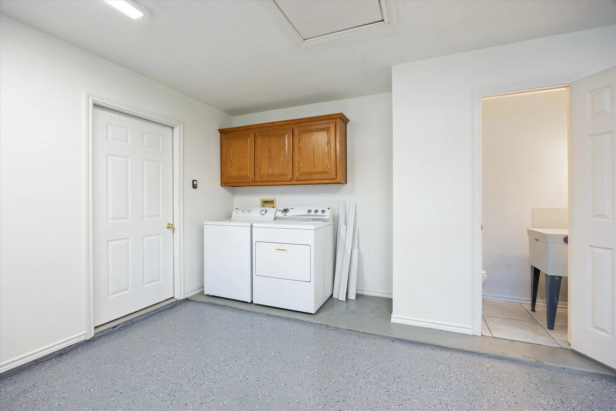 Laundry area with wood-finish upper cabinetry, and a half bath