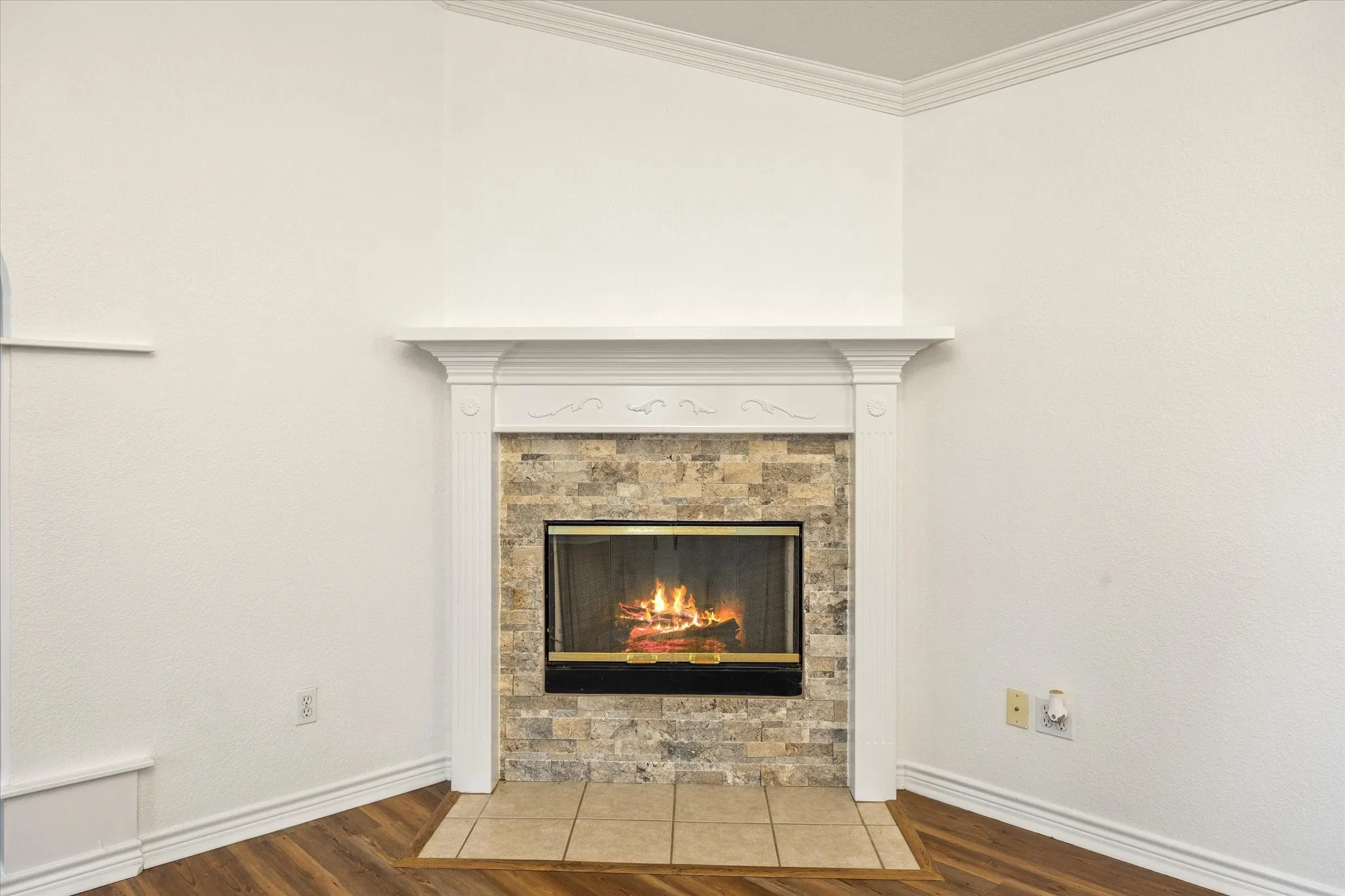 Fireplace with a stone surround, decorative mantel, glass enclosure, and tile hearth