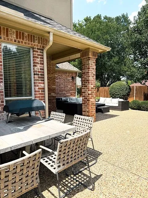 Expansive outdoor patio featuring a brick exterior and a covered area