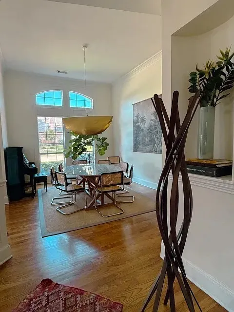 Hardwood flooring throughout, featuring a dining area with a gold bowl-shaped pendant light and arched windows