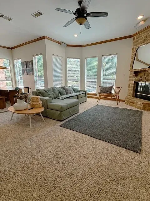 Spacious living area featuring a stone-clad fireplace, ceiling fan, recessed lighting, and multiple windows with blinds