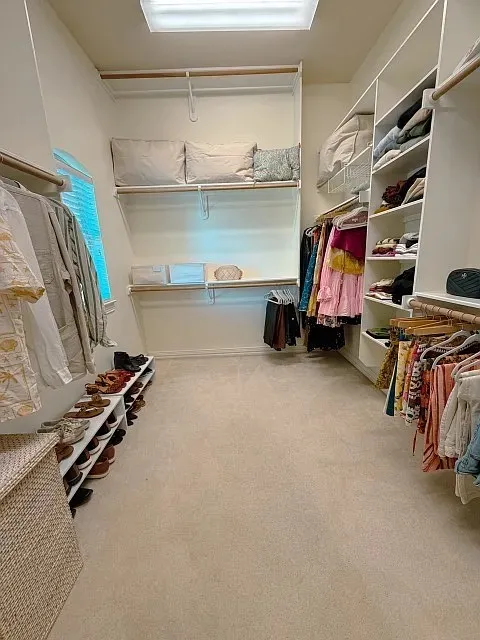 Walk-in closet featuring white built-in shelving, hanging rods, carpet flooring, and a recessed ceiling light