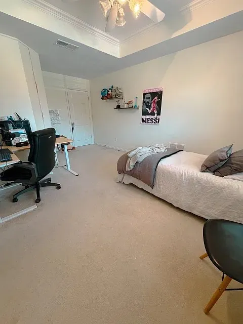 Carpeted flooring, tray ceiling with crown molding, and a ceiling fan with integrated lighting