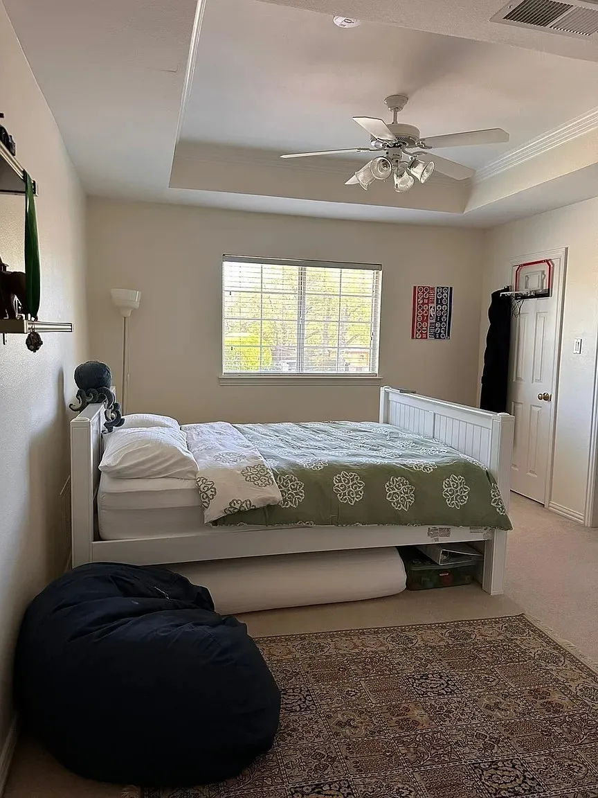 Tray ceiling with crown molding, ceiling fan with integrated lighting, window with blinds, paneled interior door, and wall-mounted shelving