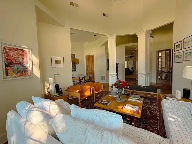 Spacious living area featuring high ceilings, decorative columns, wood-finish flooring, and French doors