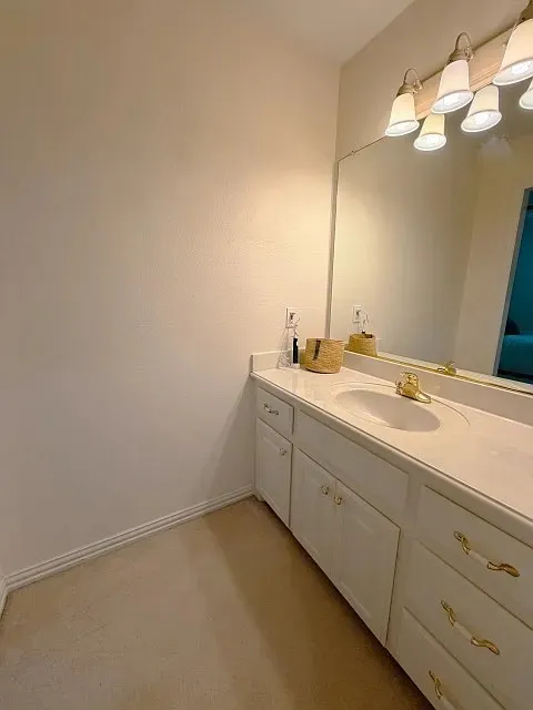 White vanity with a single integrated sink, gold-tone faucet, and a large wall-mounted mirror