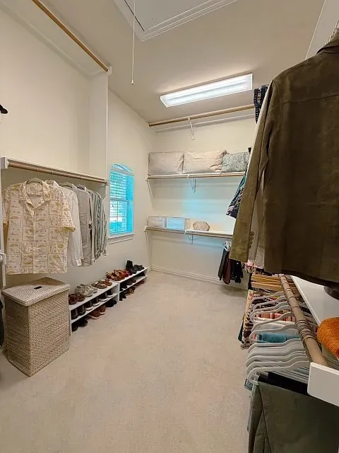 Vaulted ceiling, carpeted flooring, built-in shelving, hanging rods, arched window