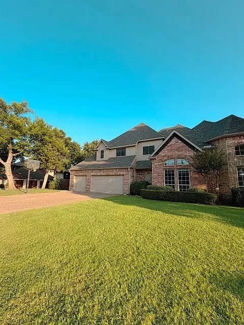 Brick and stucco exterior with multiple gables, arched windows, and a three-car garage