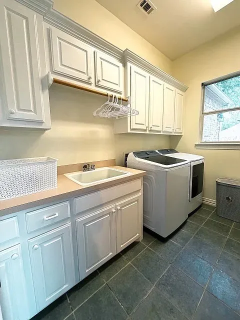 White cabinetry with crown molding, integrated sink, light-toned countertop, square tile flooring, and a window