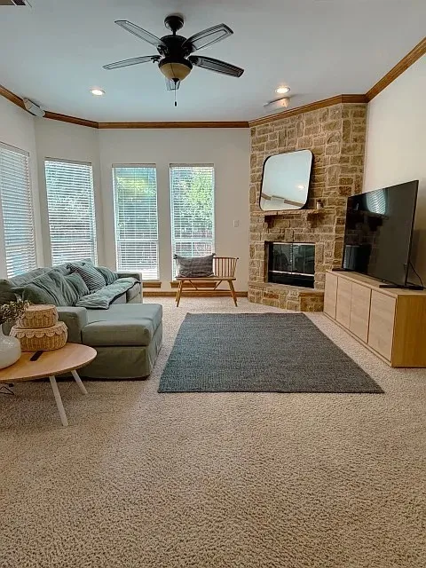 Stone-clad corner fireplace, recessed lighting, ceiling fan, and carpeted flooring