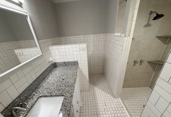 Vanity with a surface-mounted sink, speckled countertop, and built-in cabinetry