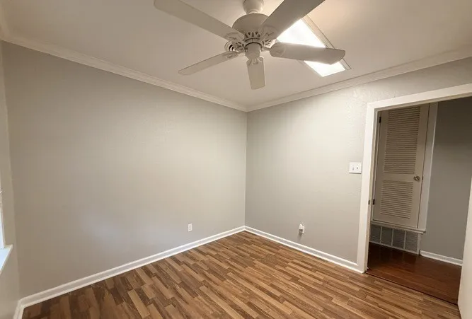 Wood-finish flooring, ceiling fan, recessed lighting, and crown molding