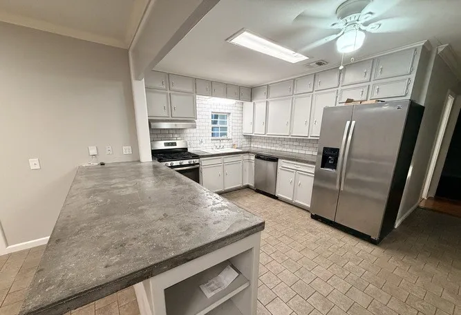 Kitchen featuring a built-in oven range, stainless steel appliances, white subway tile backsplash, and a large breakfast bar with a gray countertop