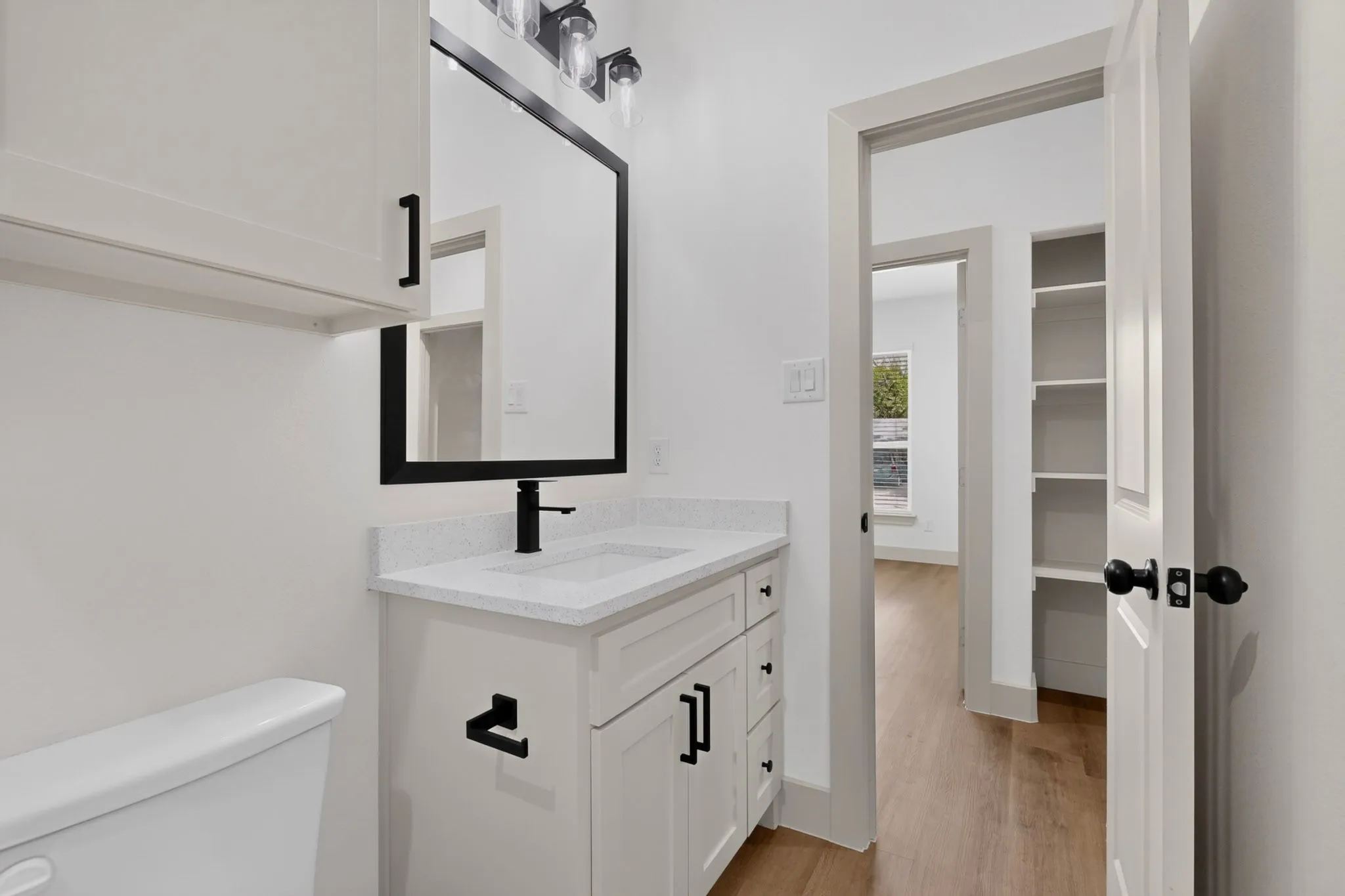 White vanity with a solid surface countertop, undermount sink, and matte black faucet