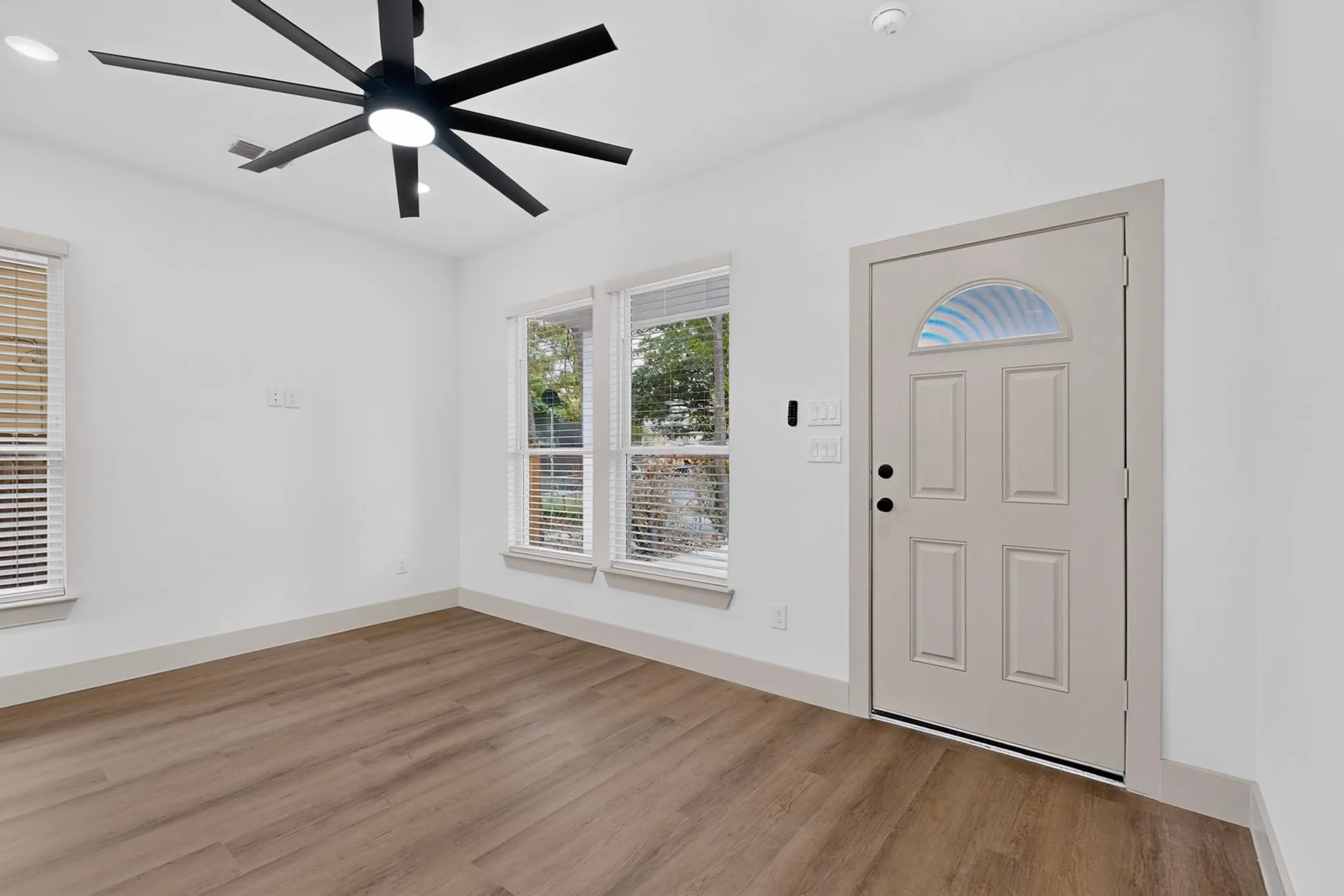 Recessed lighting, wood-finish flooring, and a large ceiling fan with integrated lighting