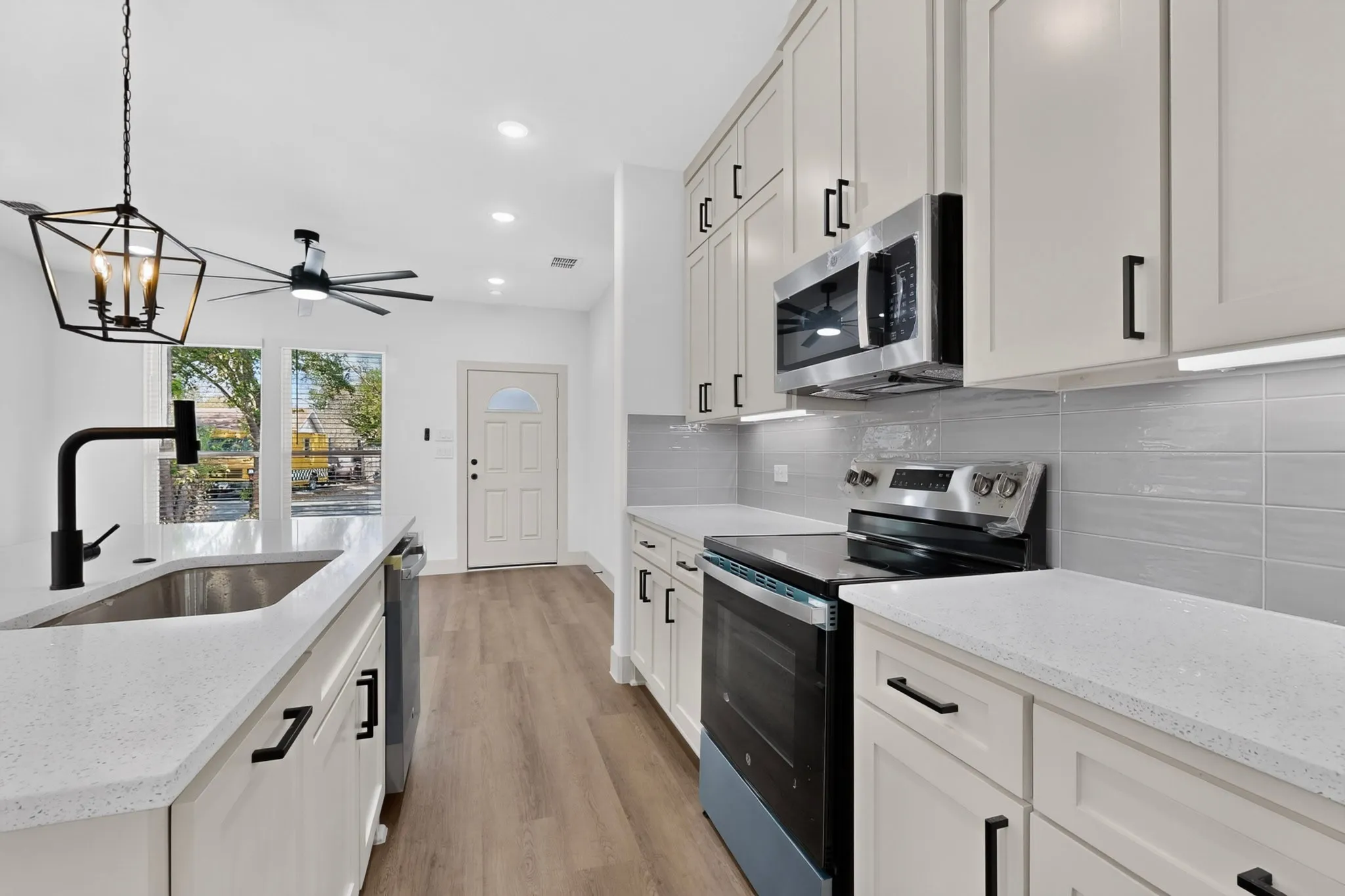 Kitchen featuring light-finish cabinetry, stainless steel appliances, light-toned countertops, and wood-finish flooring