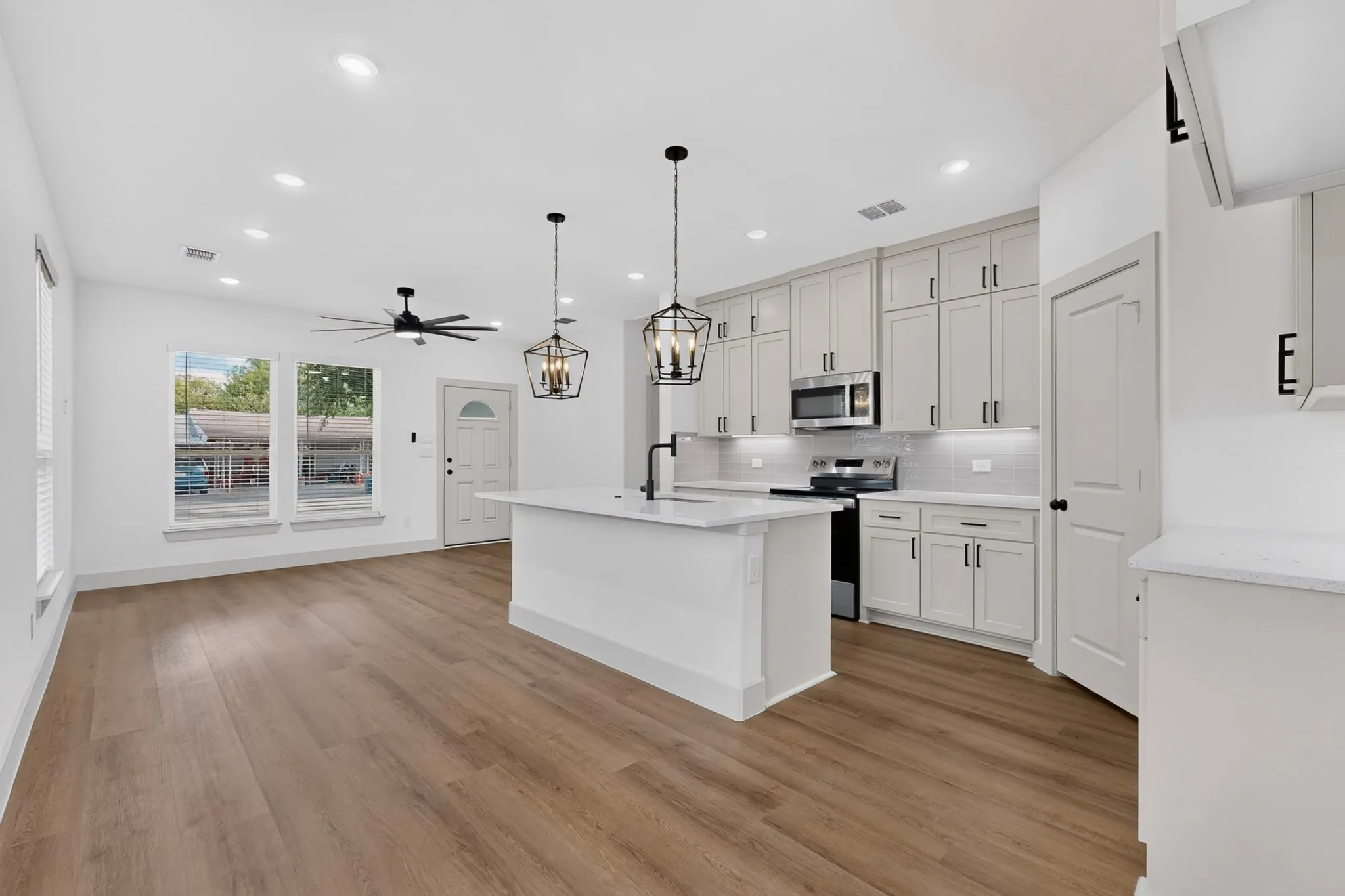 Open-concept living area featuring wood-finish flooring, recessed lighting, and a ceiling fan