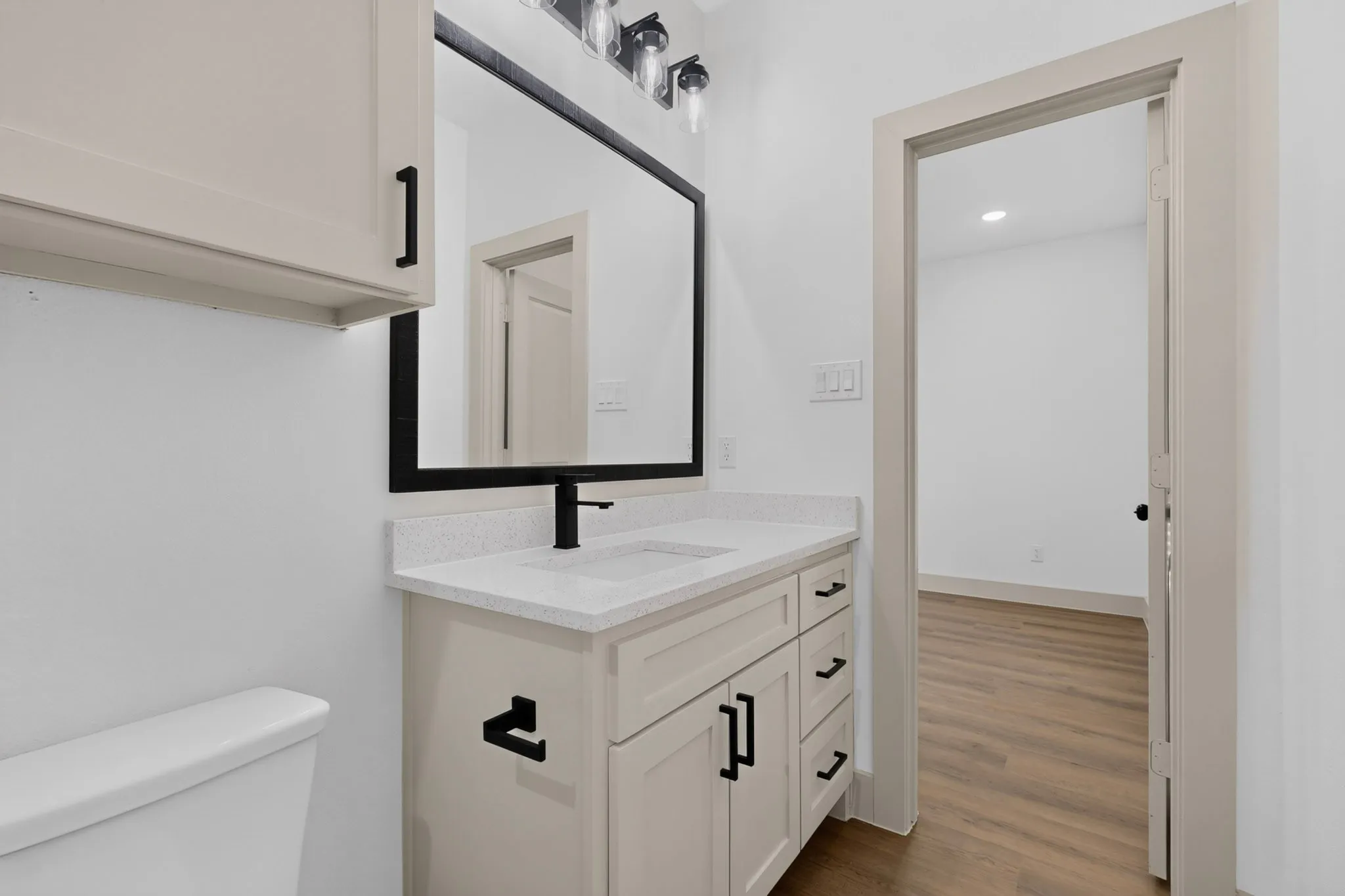 Vanity with a light-toned cabinet, white countertop, and matte black faucet