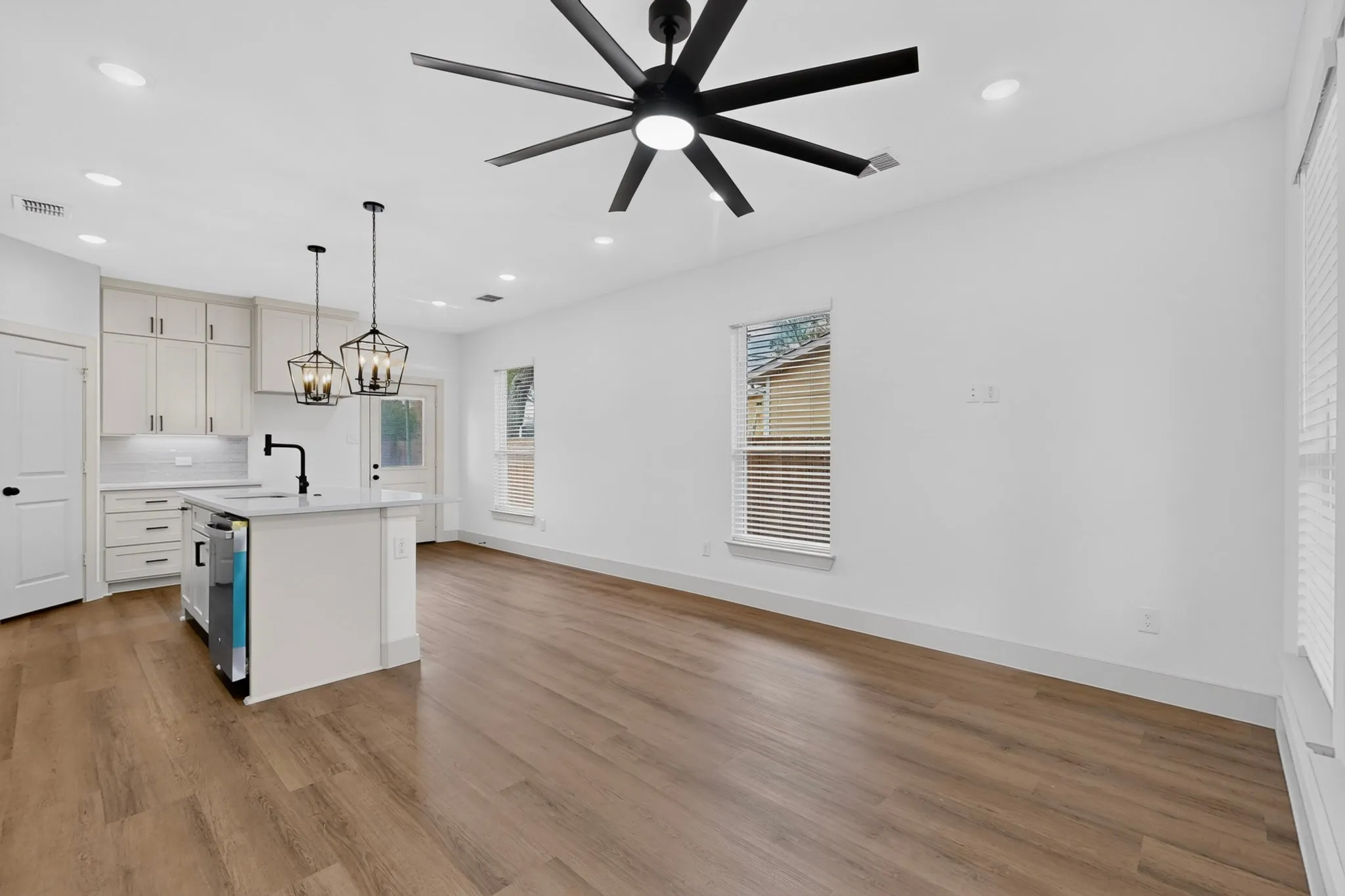 Open-concept living space with wood-finish flooring, recessed lighting, and a modern ceiling fan