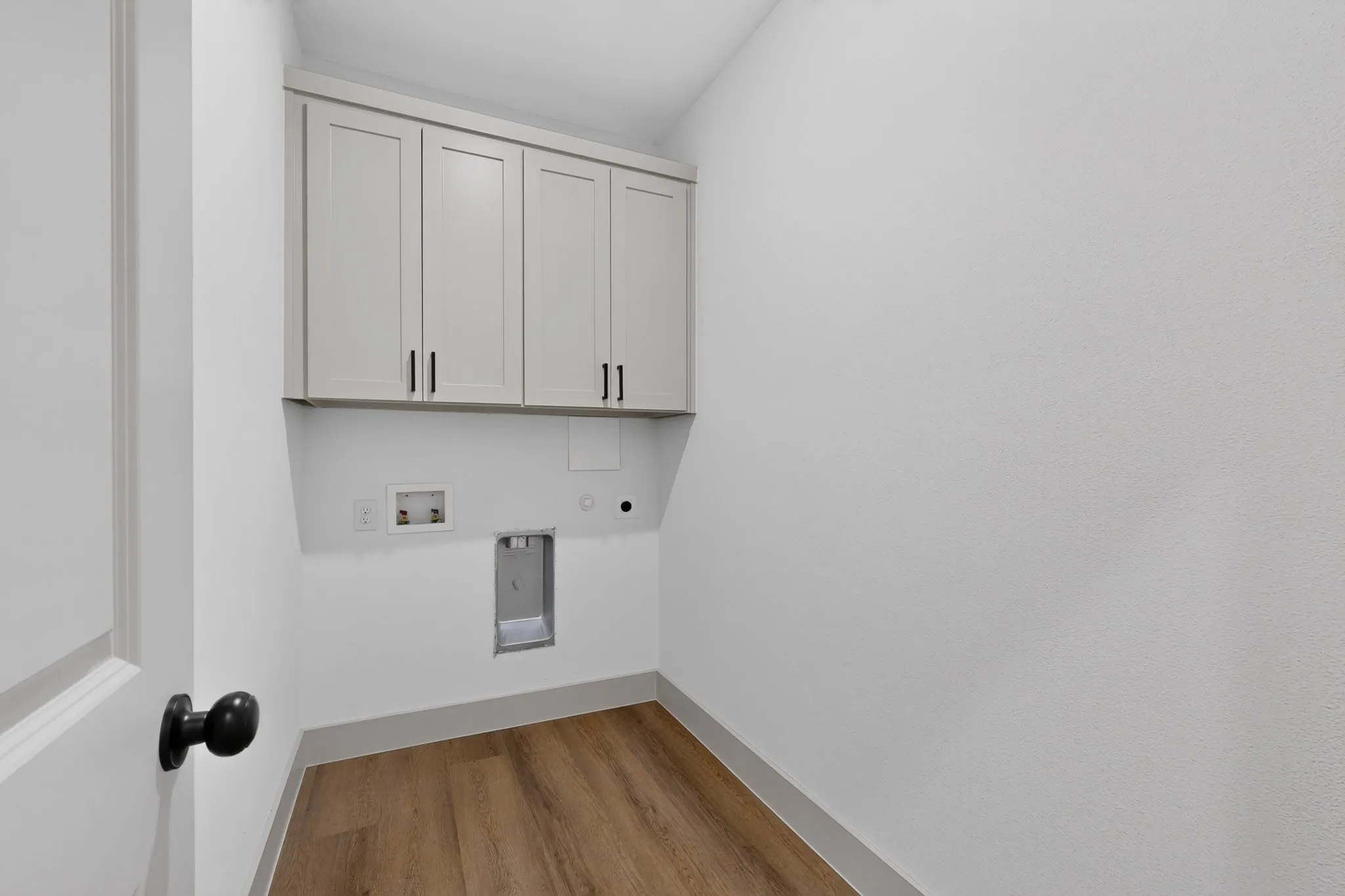 Built-in cabinetry with matte black hardware, wood-finish flooring, and crisp white walls