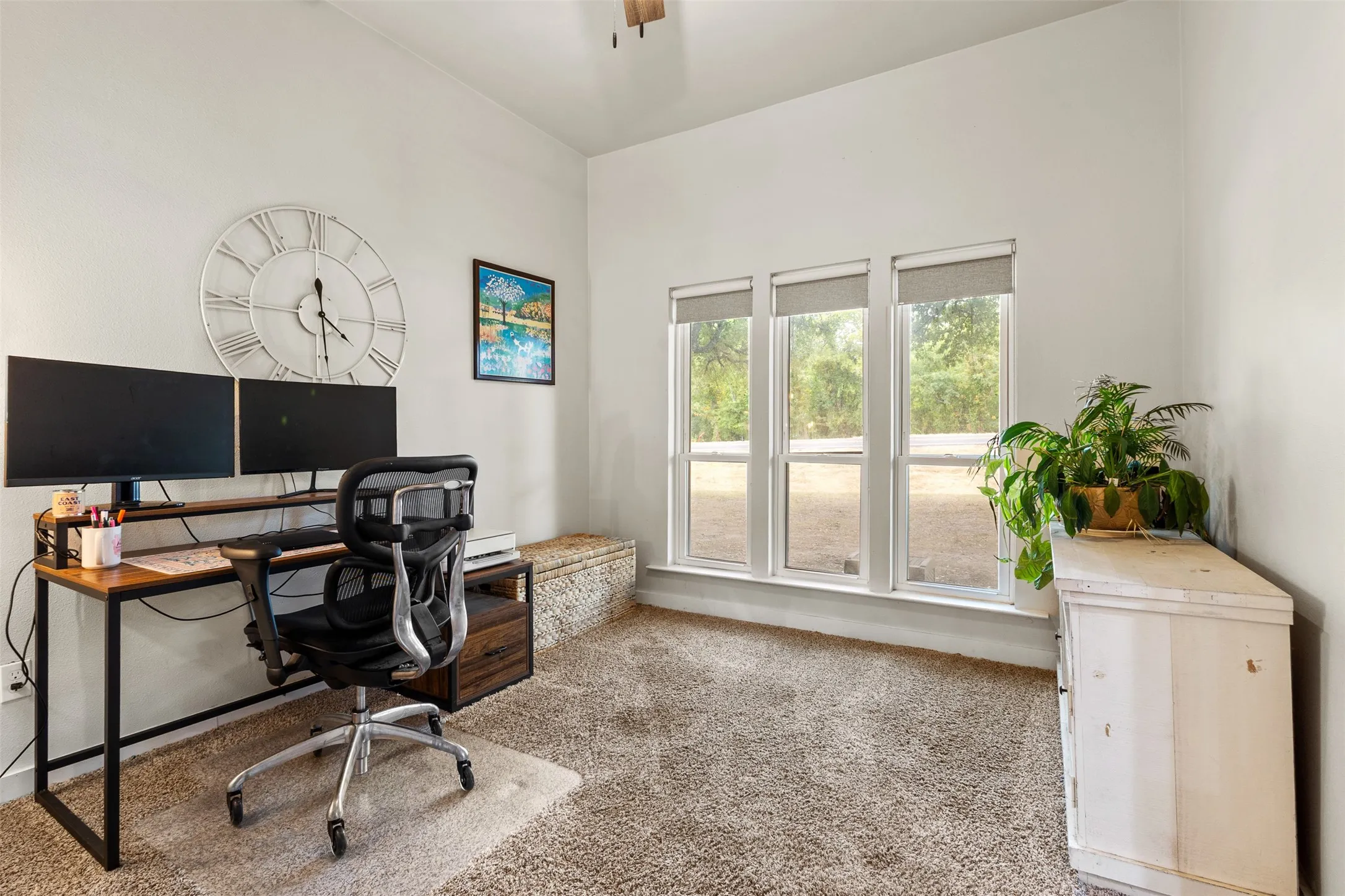 Carpeted room with white walls, three large windows, and a ceiling fan