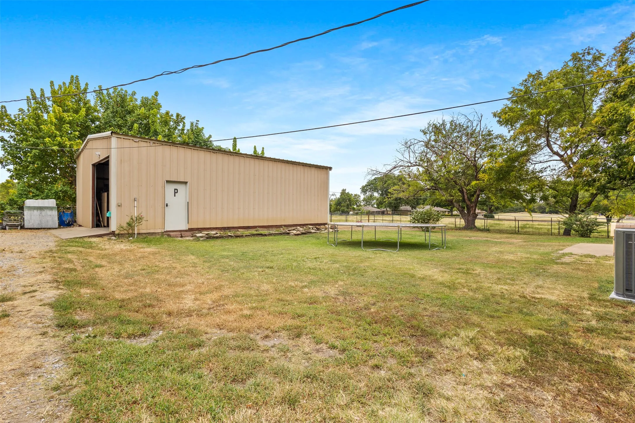 Metal outbuilding with a large roll-up door, side entry door, and perimeter landscaping