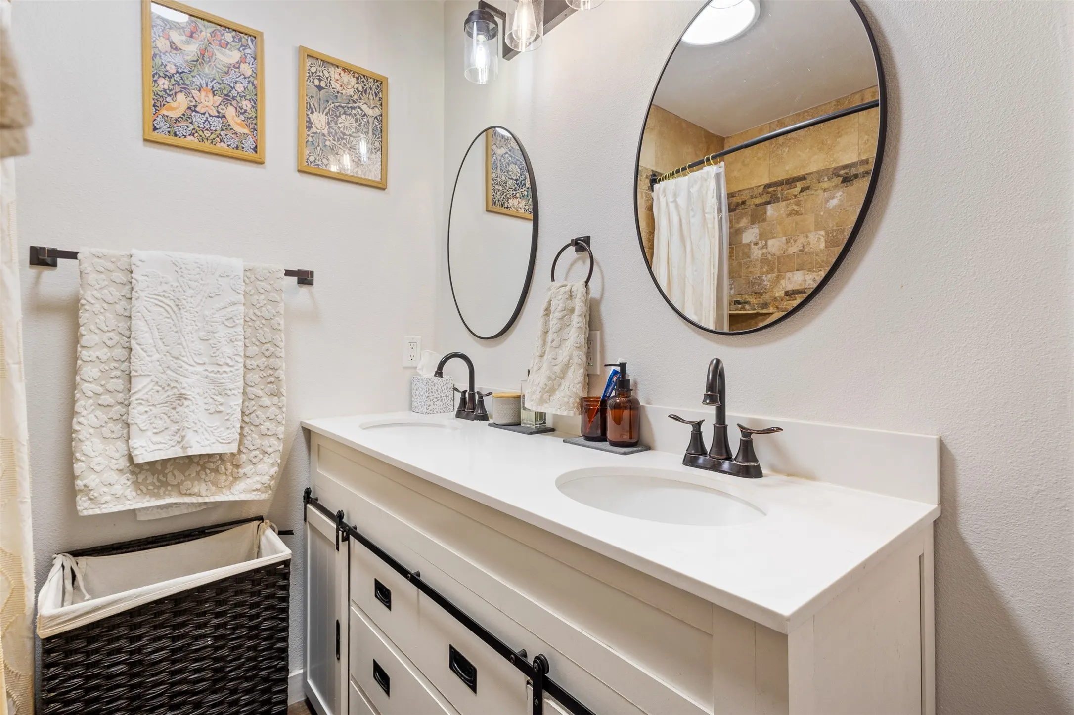 Dual vanity with white countertop, round mirrors, and dark-toned fixtures