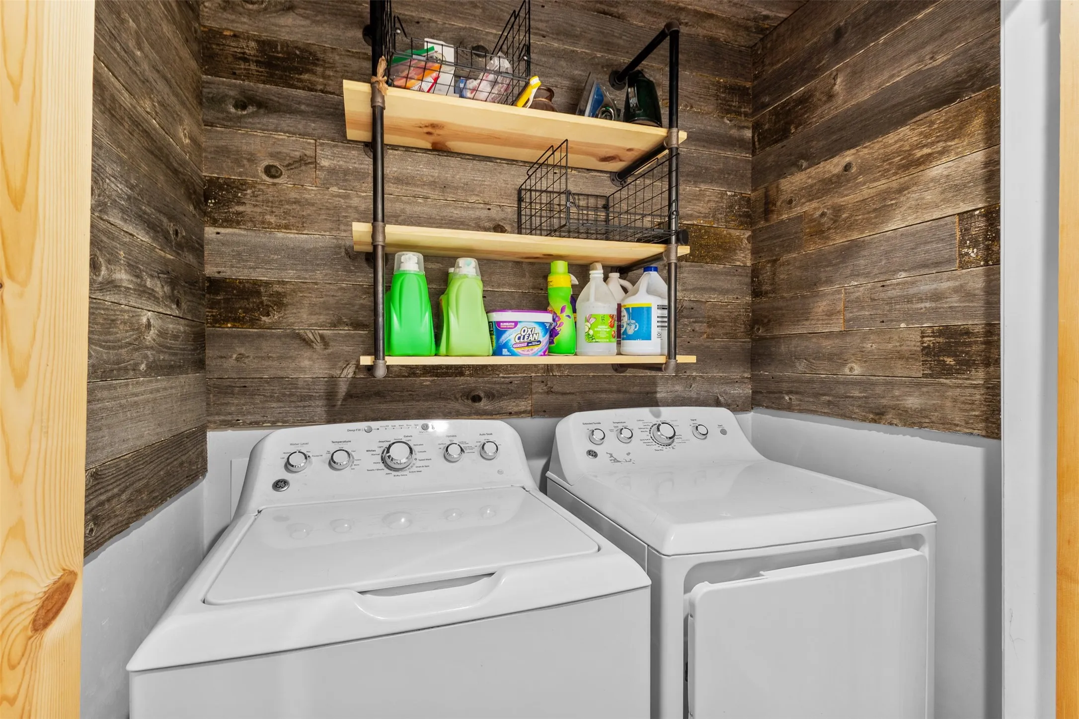 Wood-finish wall paneling with an industrial-style shelving unit featuring wood shelves and black metal piping