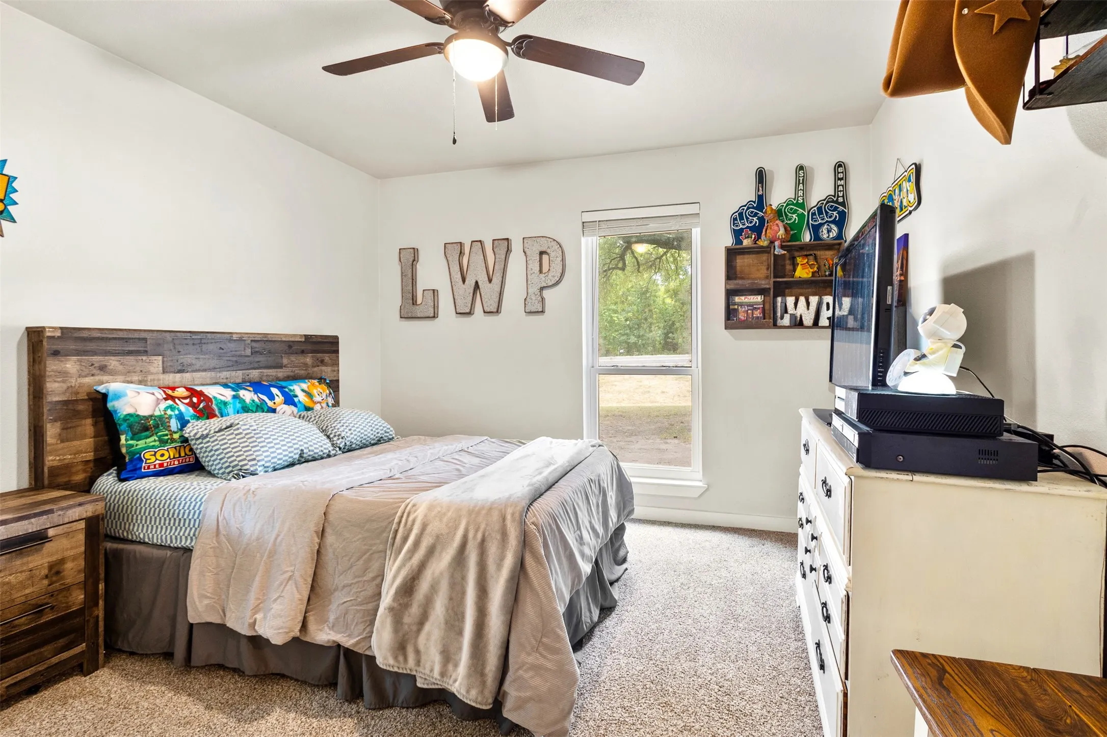 Recessed window, wood-look headboard, ceiling fan with integrated lighting, wood-finish flooring, built-in shelving