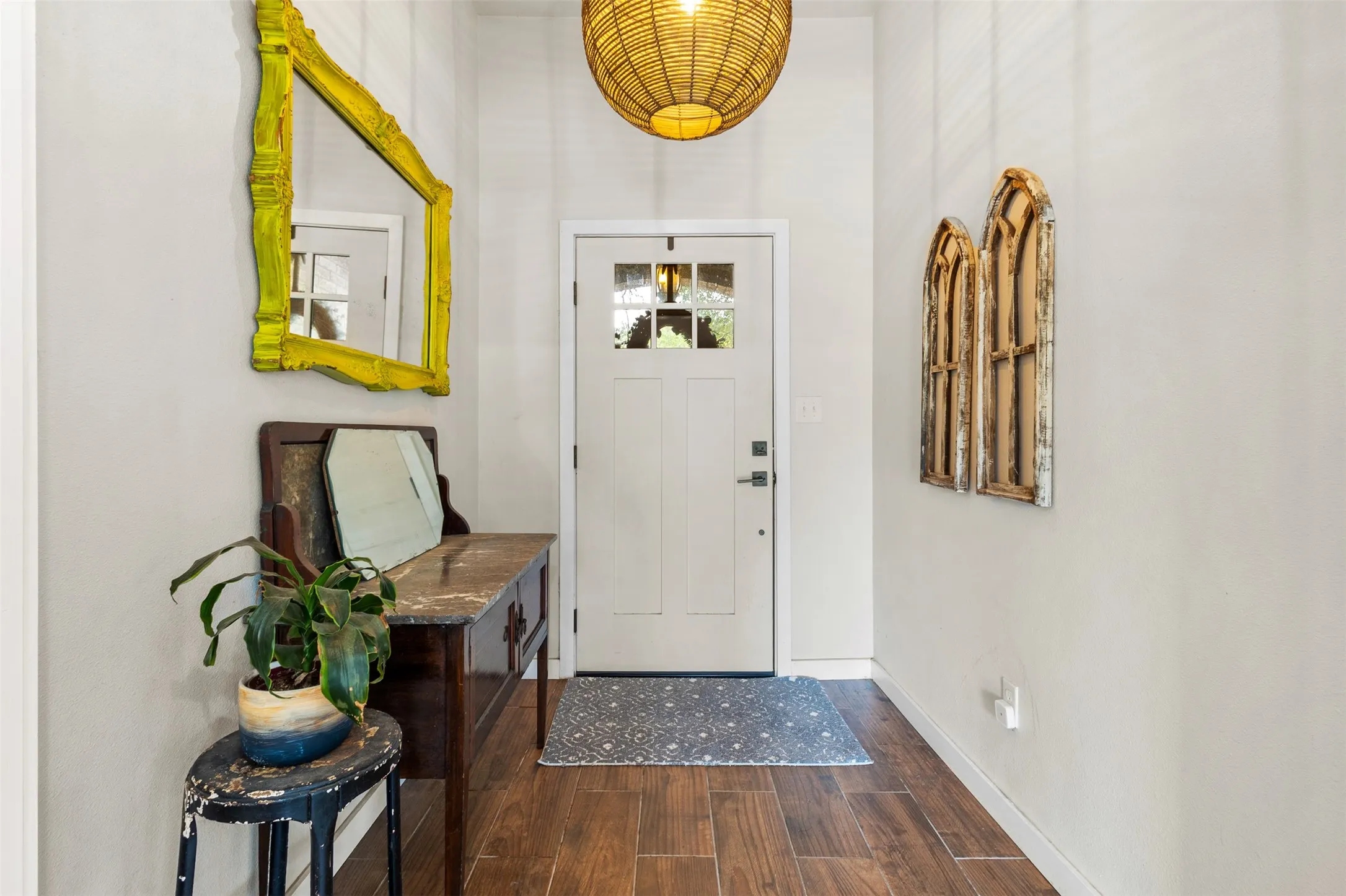 Craftsman-style entry door with glass panels, wood-finish flooring, and overhead pendant lighting