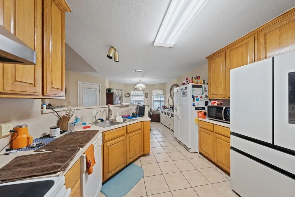 Kitchen featuring wood-finish cabinetry, tile flooring, recessed lighting, and a stainless-steel range hood