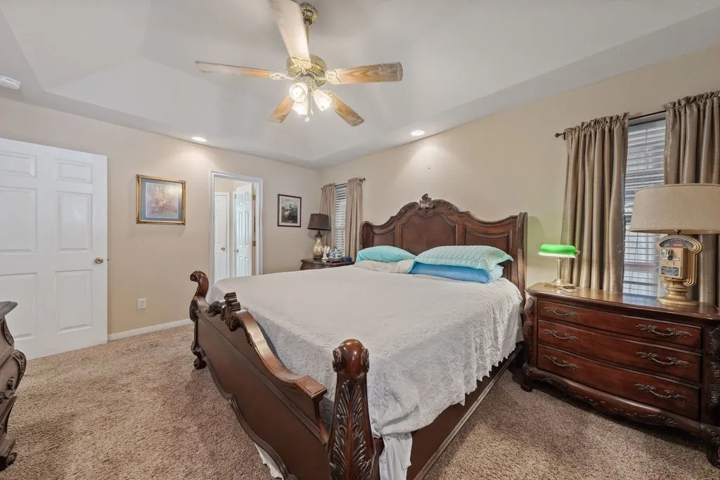 Tray ceiling with a ceiling fan, recessed lighting, and soft pile carpeting