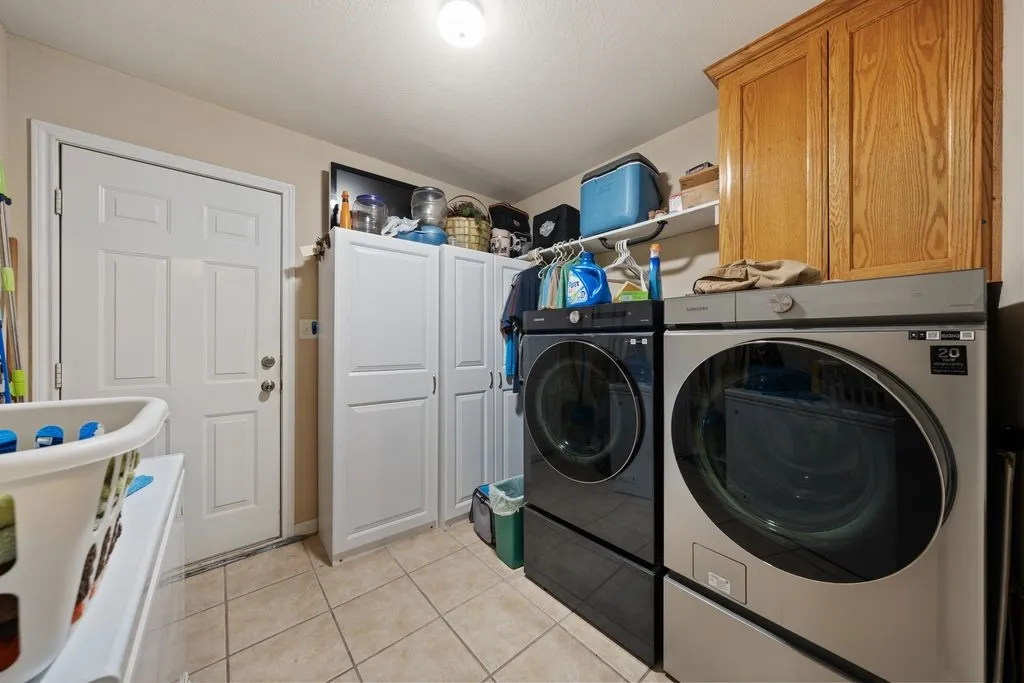 Recessed ceiling light, white paneled door, white built-in storage cabinetry, wood-finish cabinetry, and tile flooring