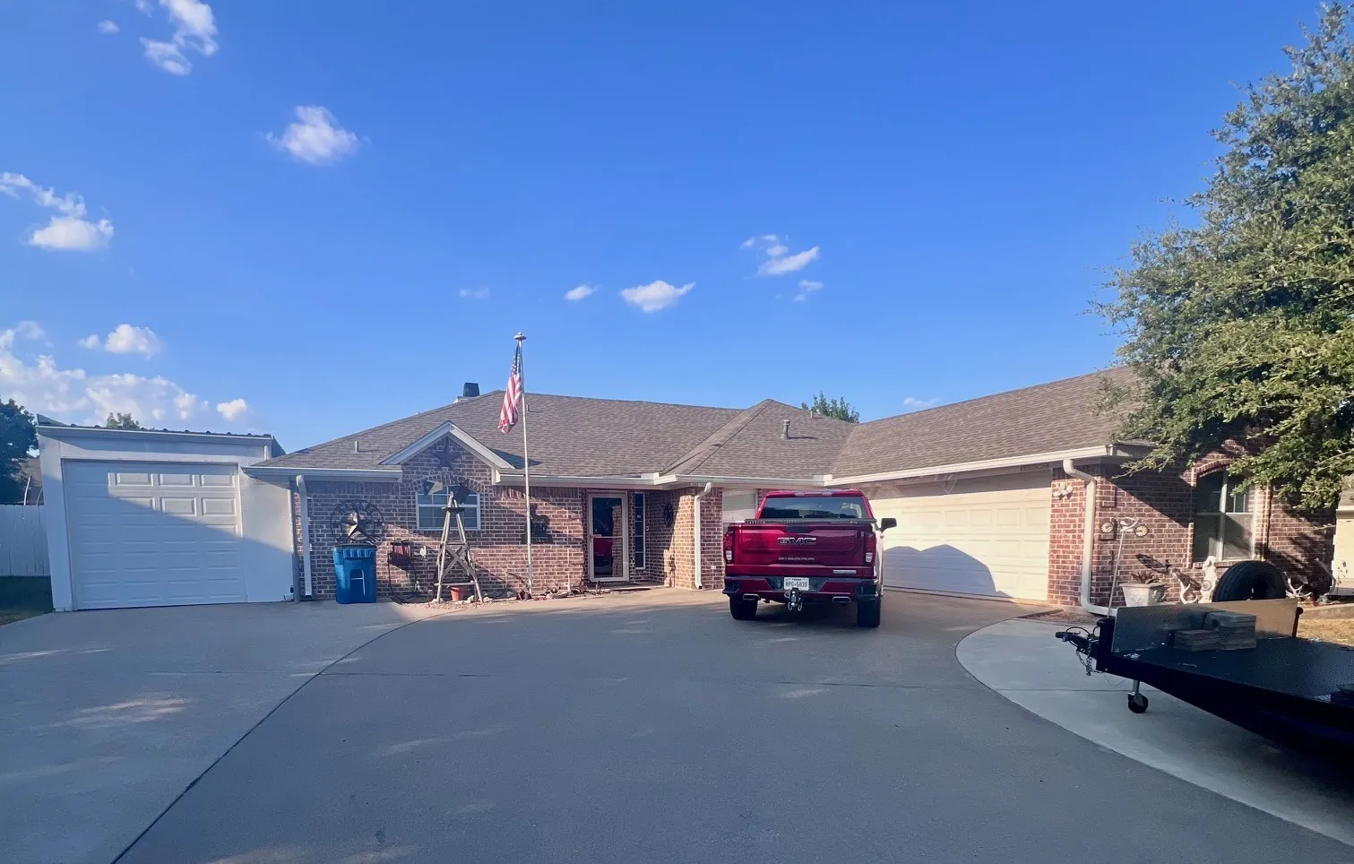 Brick exterior residence with an attached two-car garage, an additional detached single-car garage, a concrete driveway, and a shingled roof