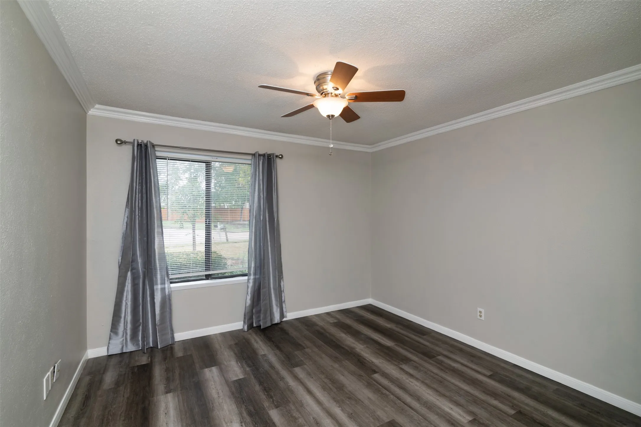 Wood-finish flooring, crown molding, ceiling fan with light fixture, and a double-pane window