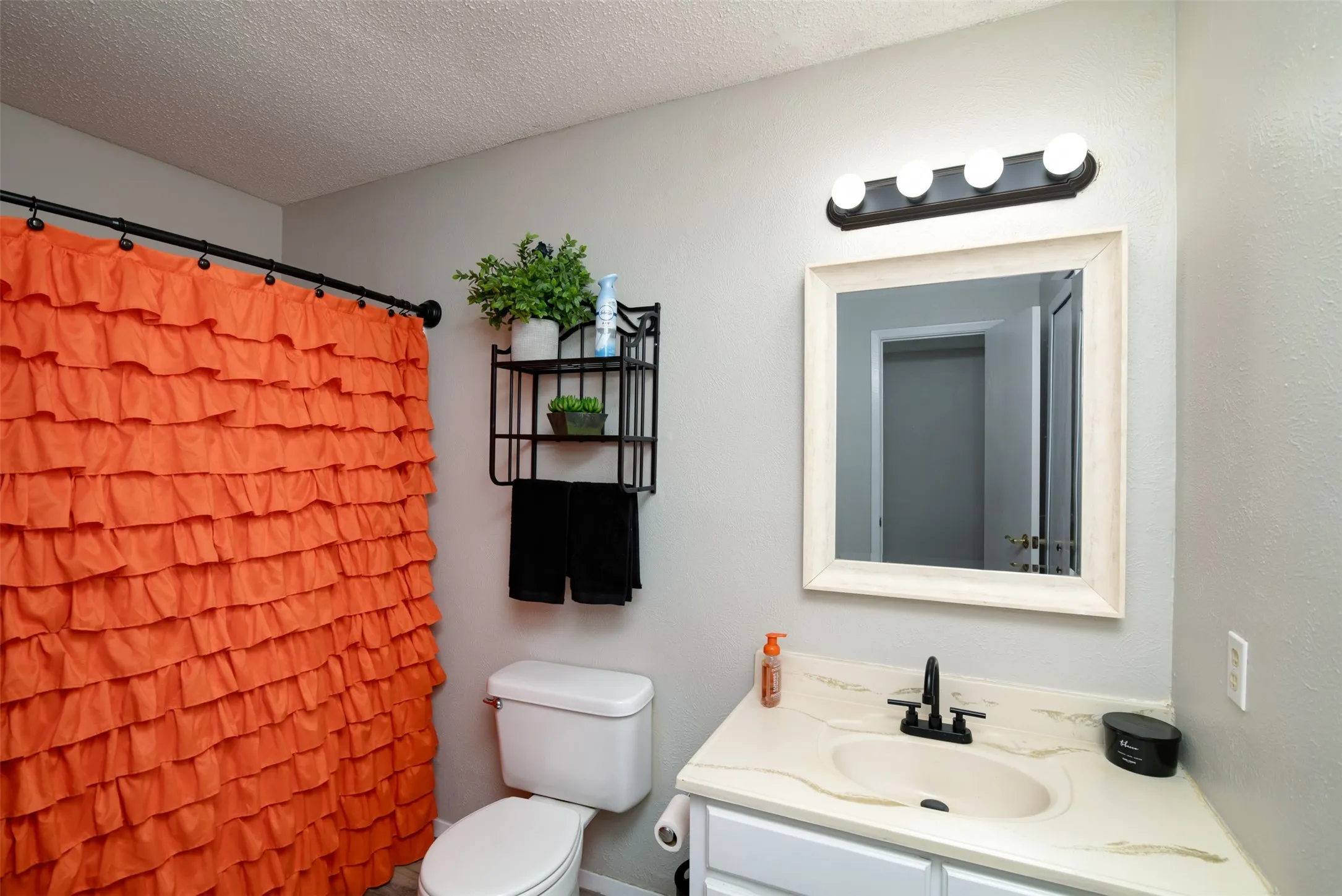 Vanity with an integrated sink, framed mirror, and a wall-mounted light fixture