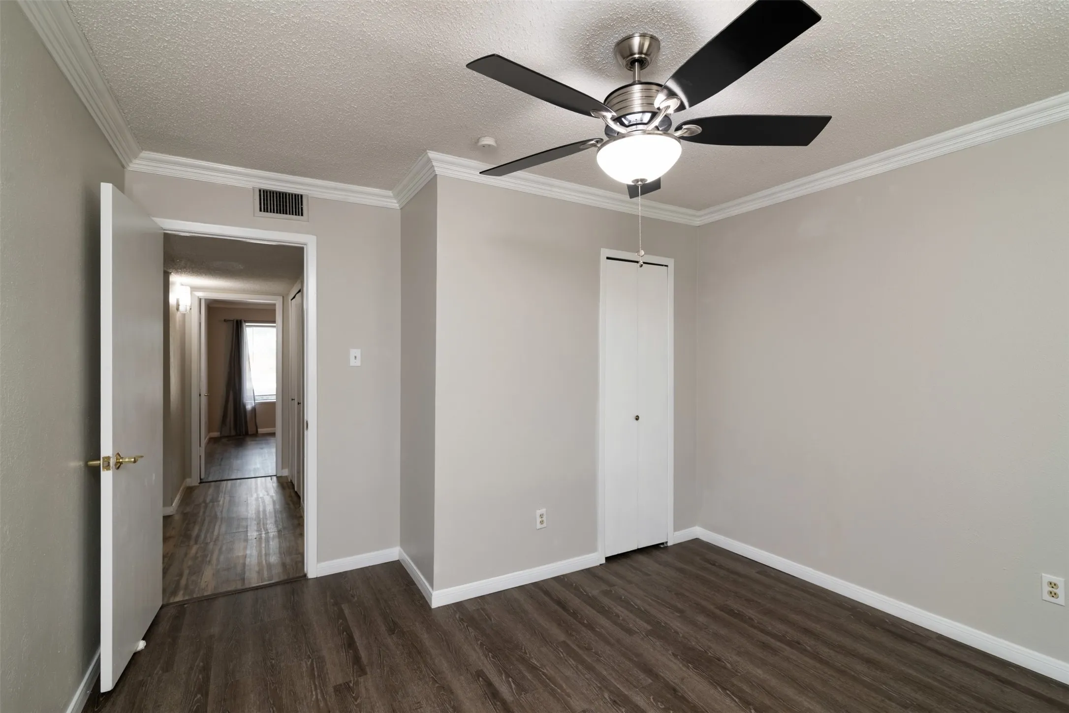 Wood-finish flooring, crown molding, ceiling fan with light fixture, and bifold closet door
