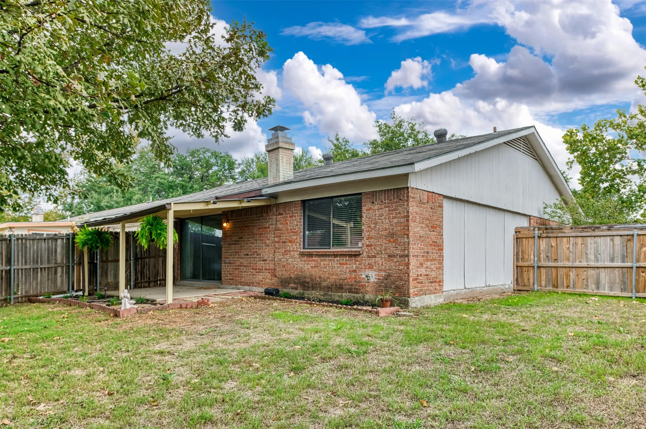 Brick exterior construction with a covered patio, sliding glass door, and a privacy fence