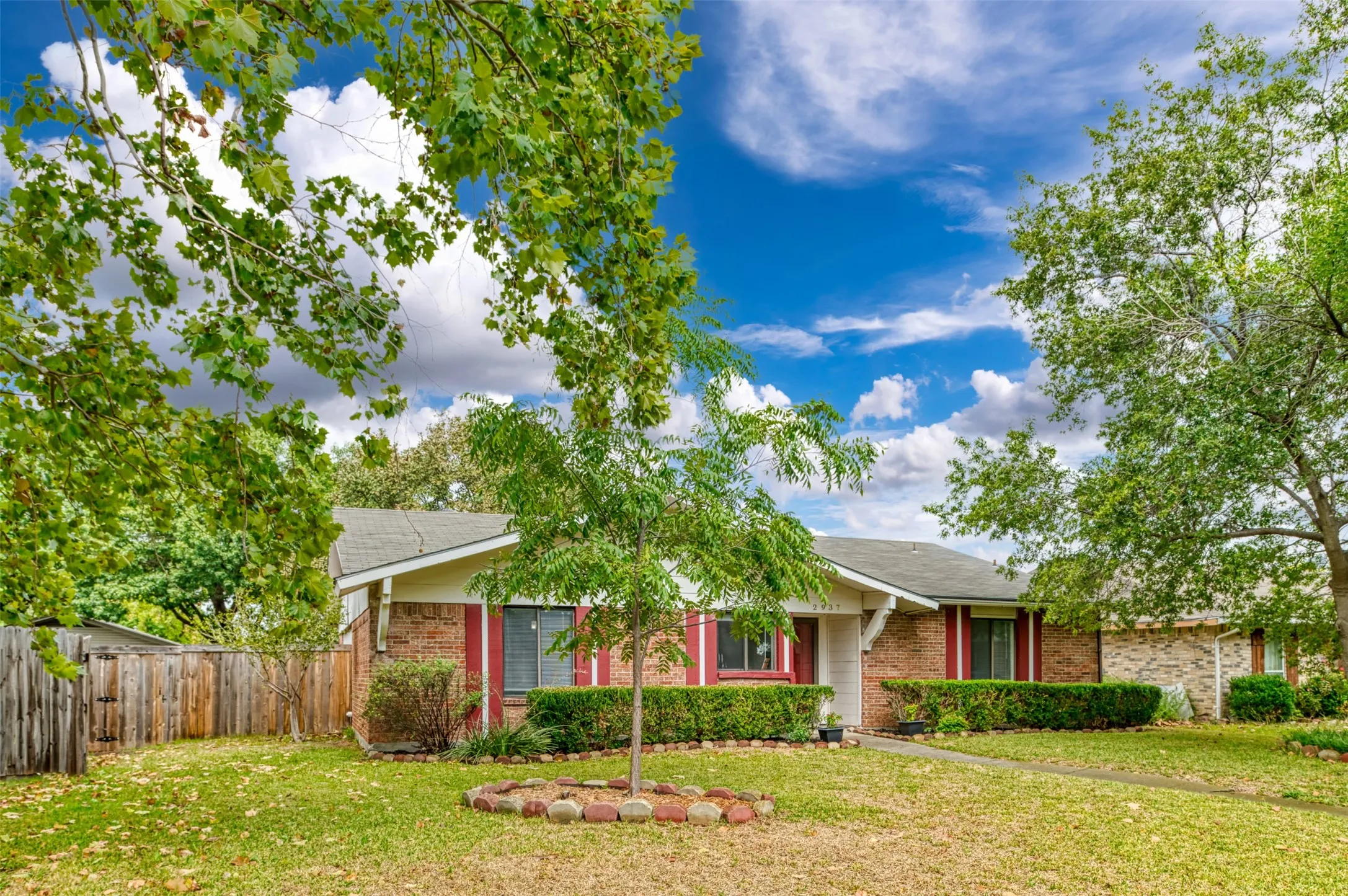 Brick exterior with red shutters, a gabled roof, and a wood privacy fence
