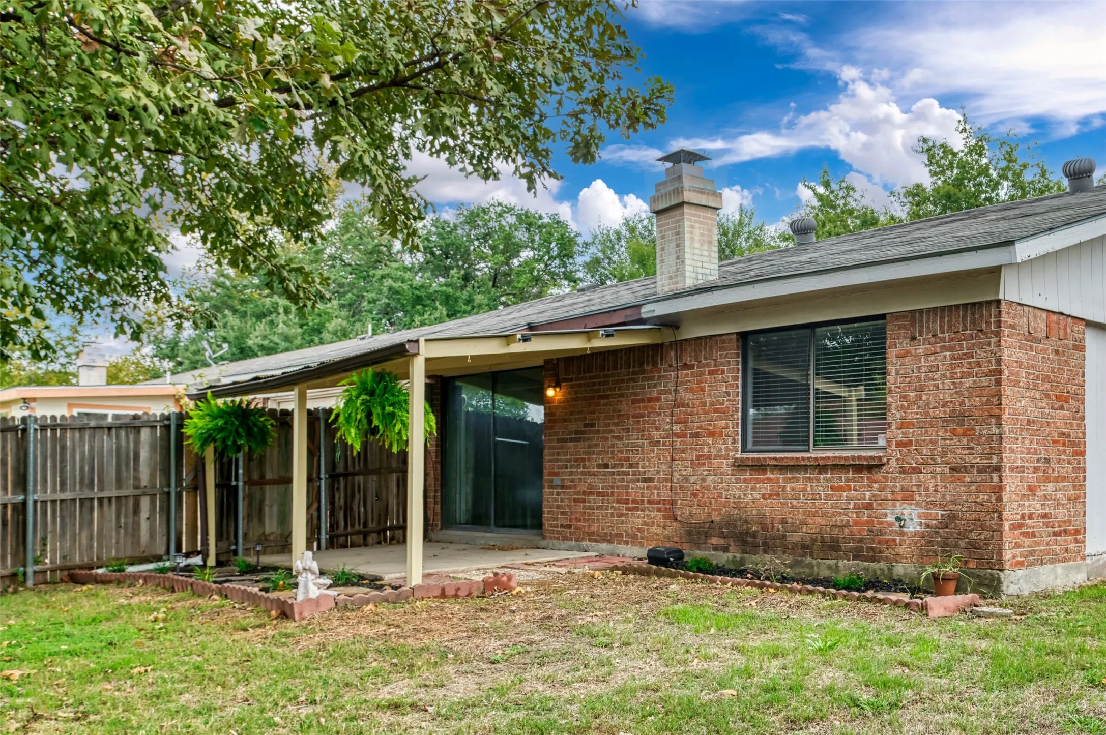Red brick exterior featuring a covered patio, sliding glass door, and a traditional chimney