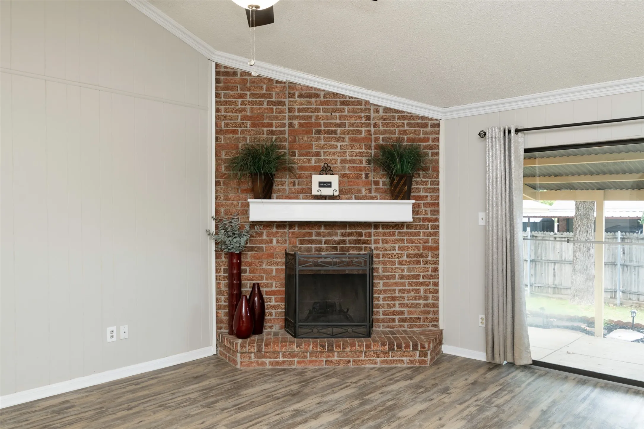 Brick fireplace with a white mantel, wood-finish flooring, and a sliding glass door