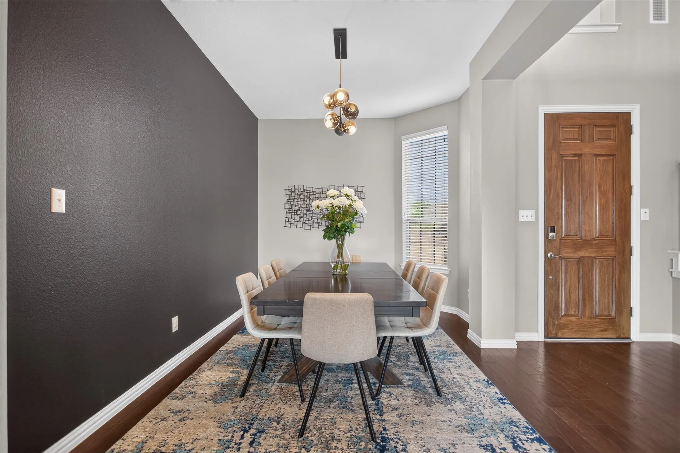 Wood-finish flooring throughout, featuring a natural wood-panel entry door and a contemporary chandelier