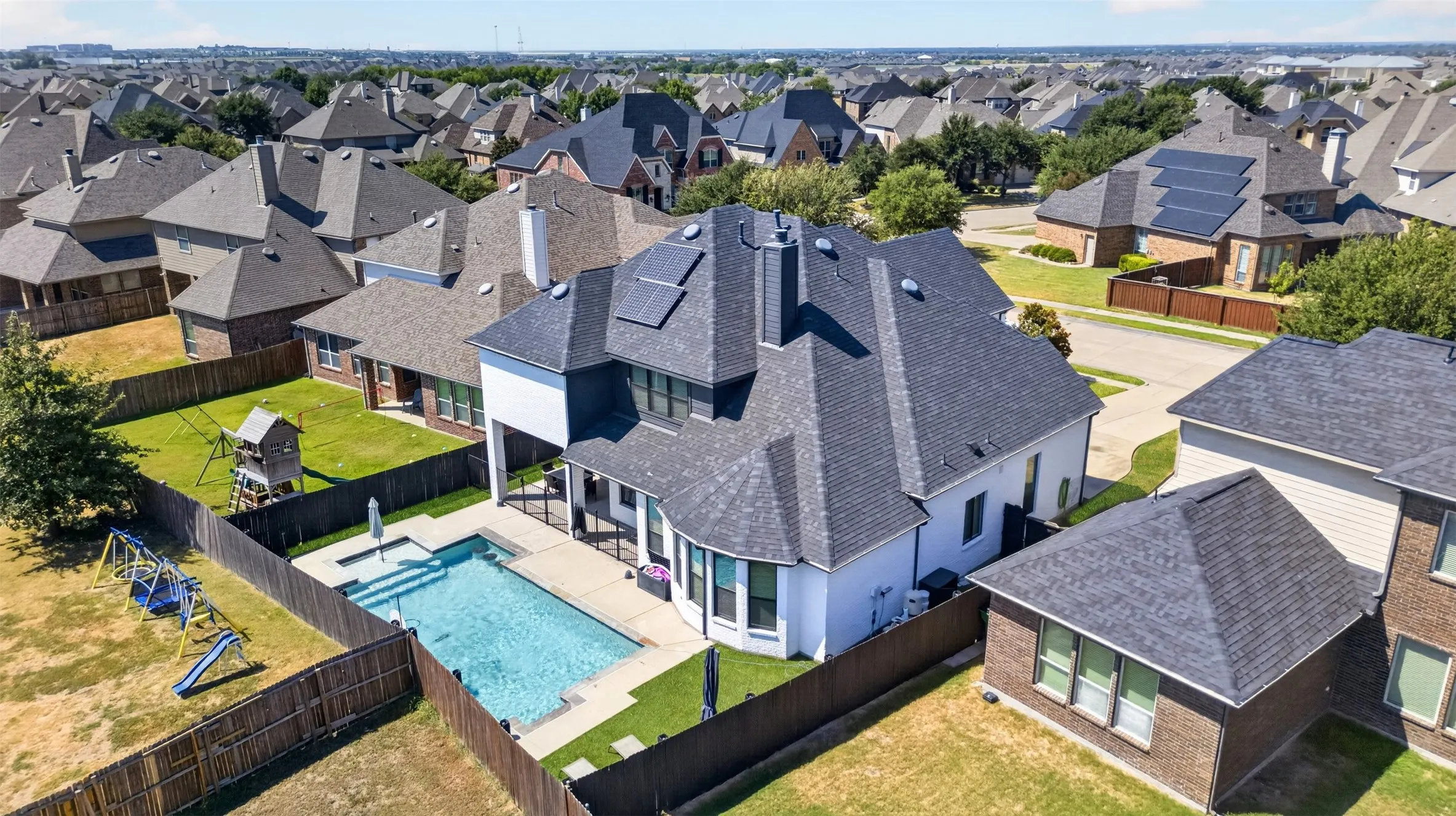 Shingled roof with solar panels, backyard swimming pool, covered patio, and fenced yard