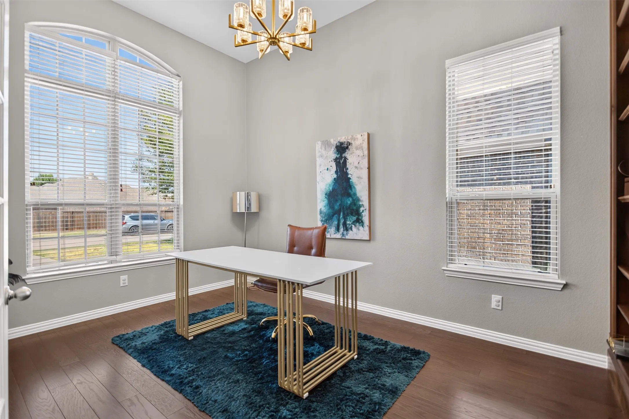 Dark wood-finish flooring, light gray wall color, and a golden chandelier