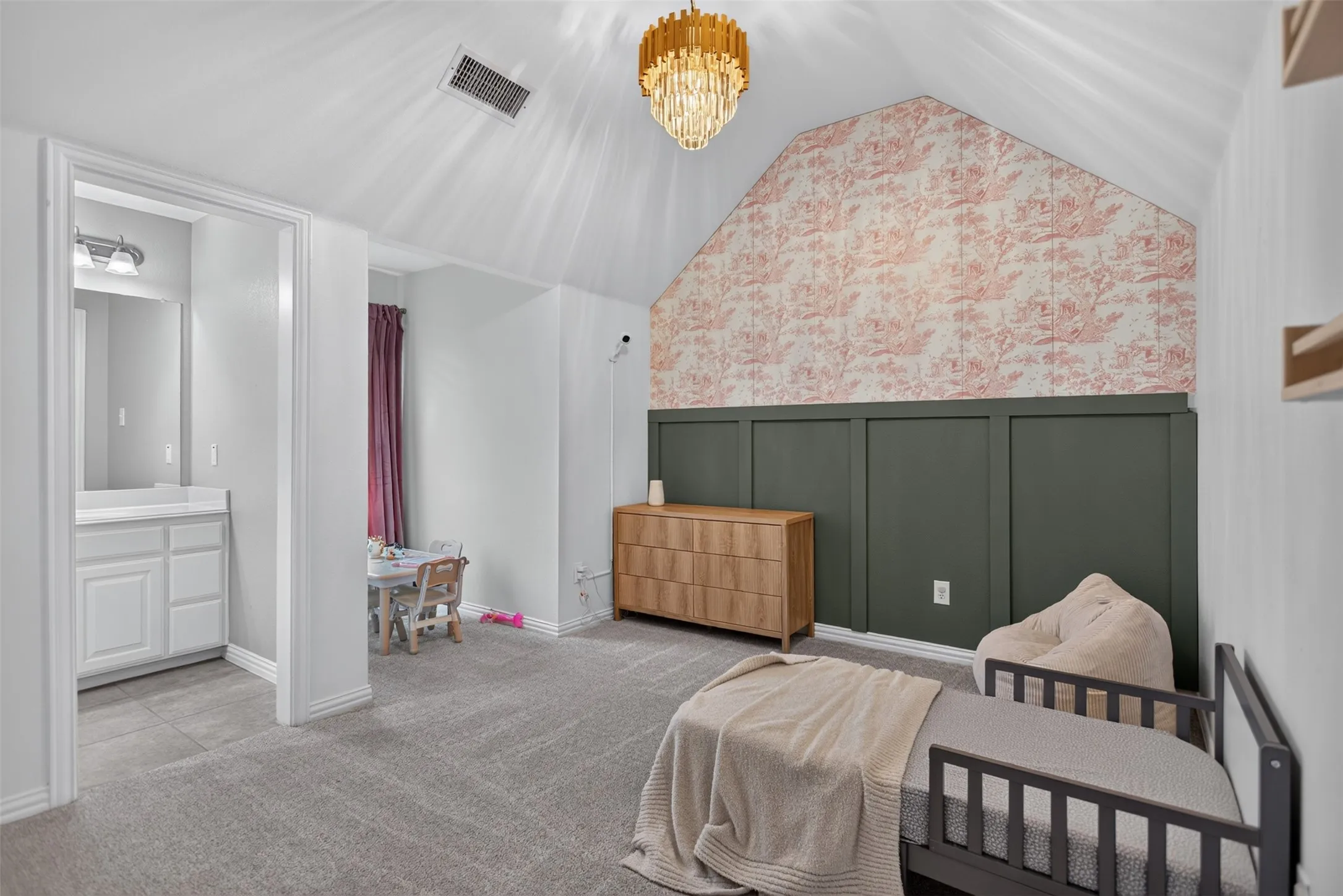 Vaulted ceiling with an ornate chandelier, accent wall with board and batten detailing, and an attached vanity with a single basin sink