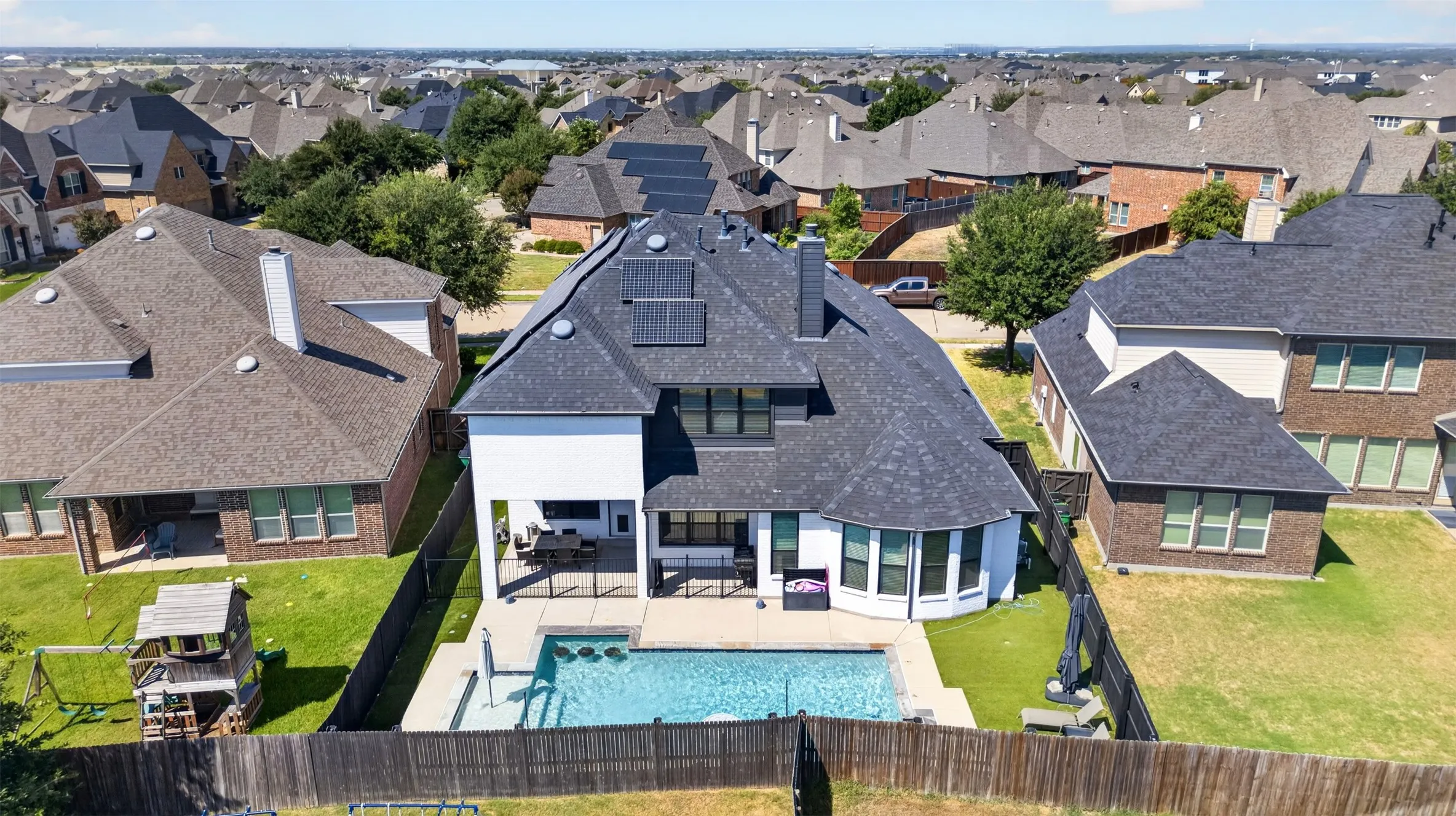 In-ground swimming pool with integrated spa, fenced backyard, exterior patio, solar panels, and a gabled roof