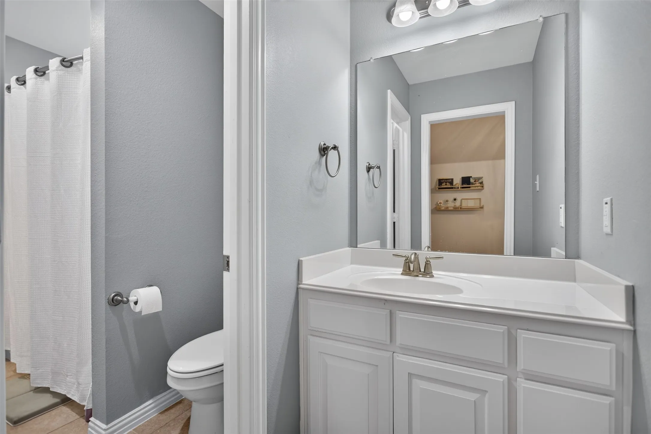 White vanity with a built-in sink, brushed nickel faucet, and a large wall-mounted mirror